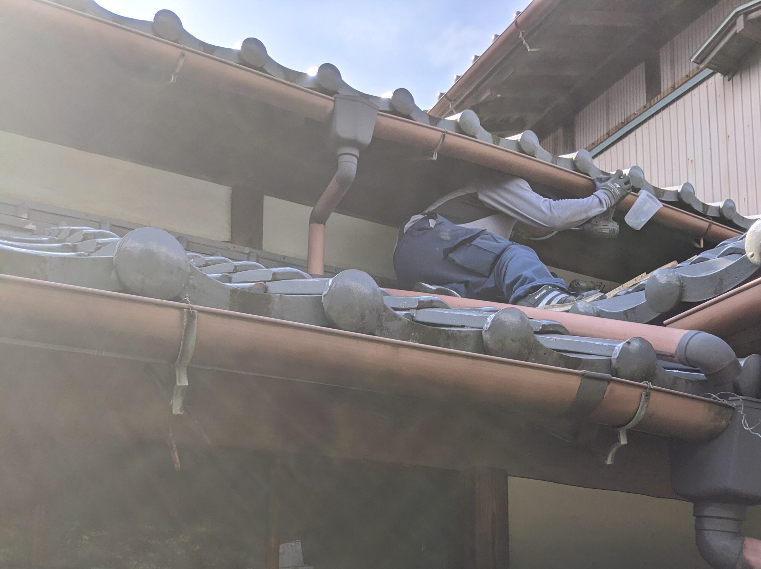 ハクビシン駆除作業員が瓦屋根の隙間を塞いで侵入口を塞ぐ